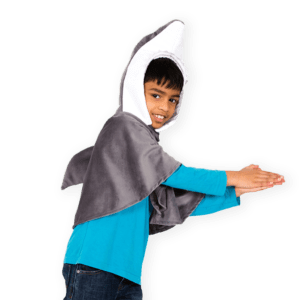 Child wearing a shark themed costume cape for kids. A grey plush hooded cape with padded shark fin